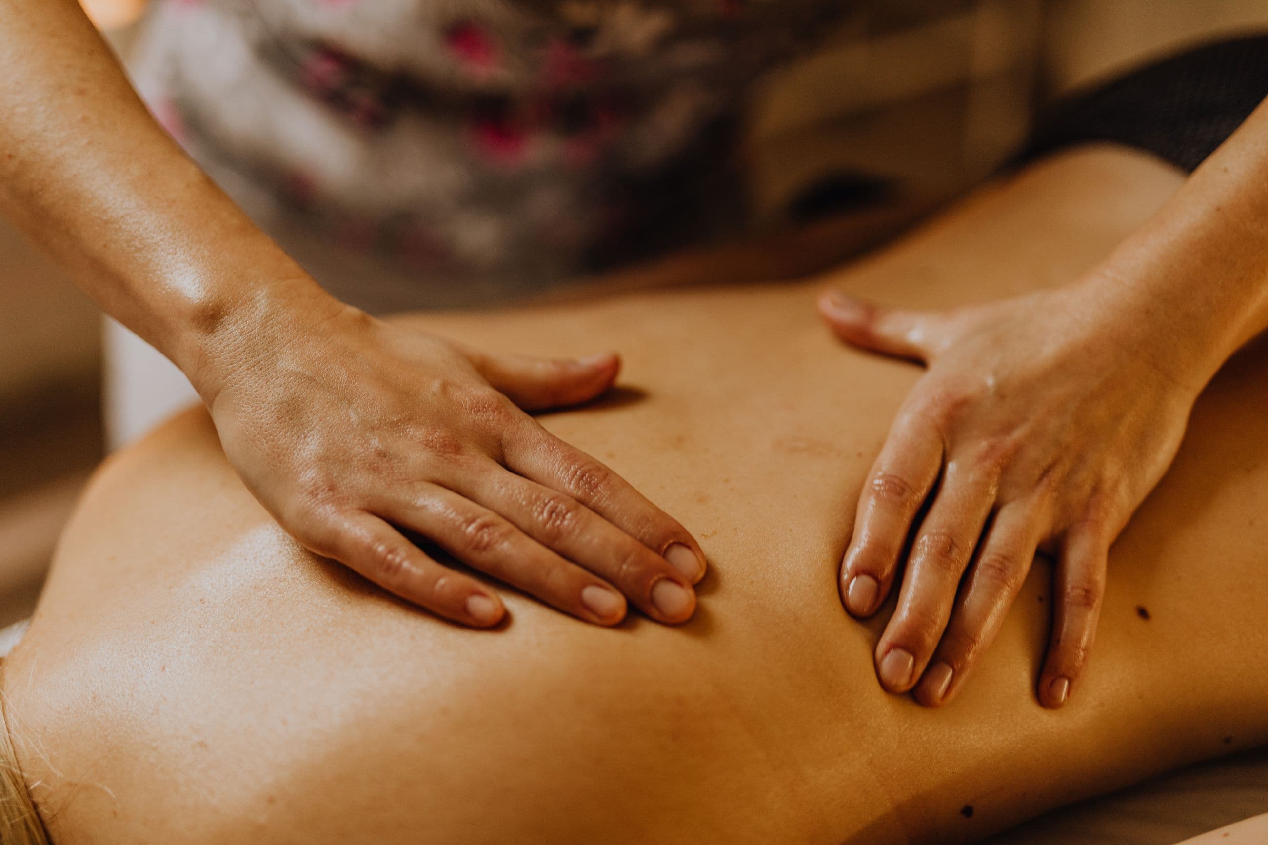 Massage therapist's hands giving a relaxing back massage with natural oil